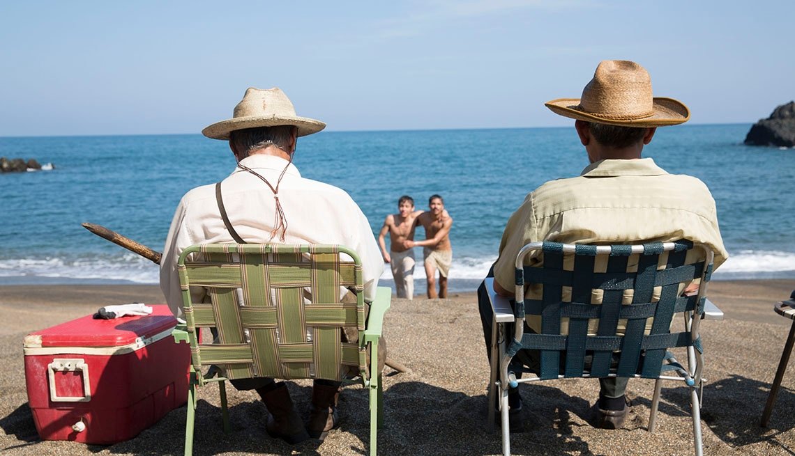 Sueño en otro idioma Dos señores en la playa con sombreros sentados uno alado del otro en camastros mirando hacia el mar en un día soleado muy bonito